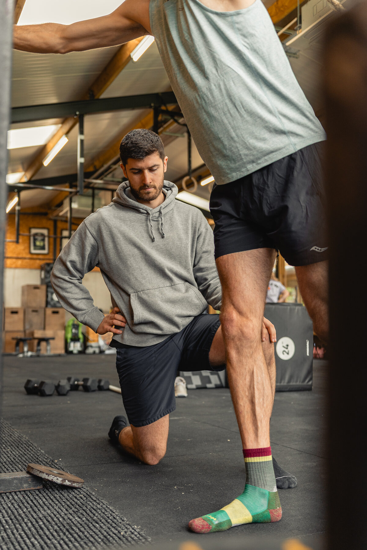 Liam Burke kneeling to assess a client's lower-body movement during a coaching session